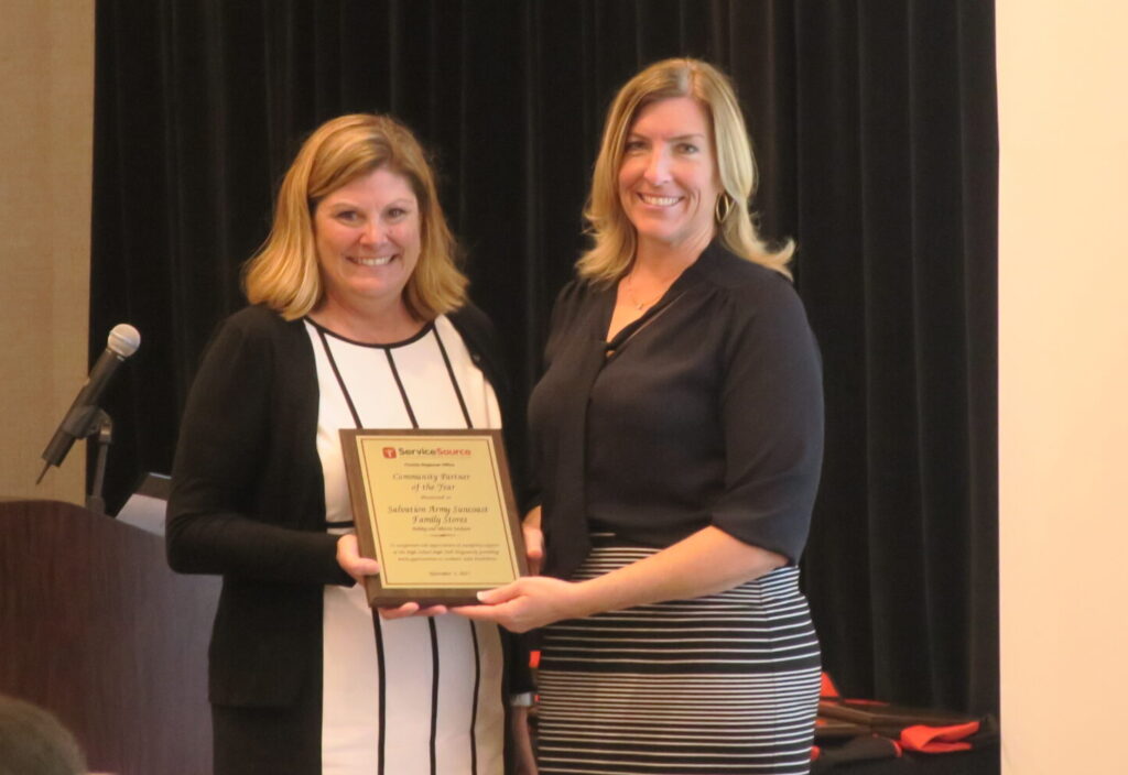 two people smiling at camera holding plaque