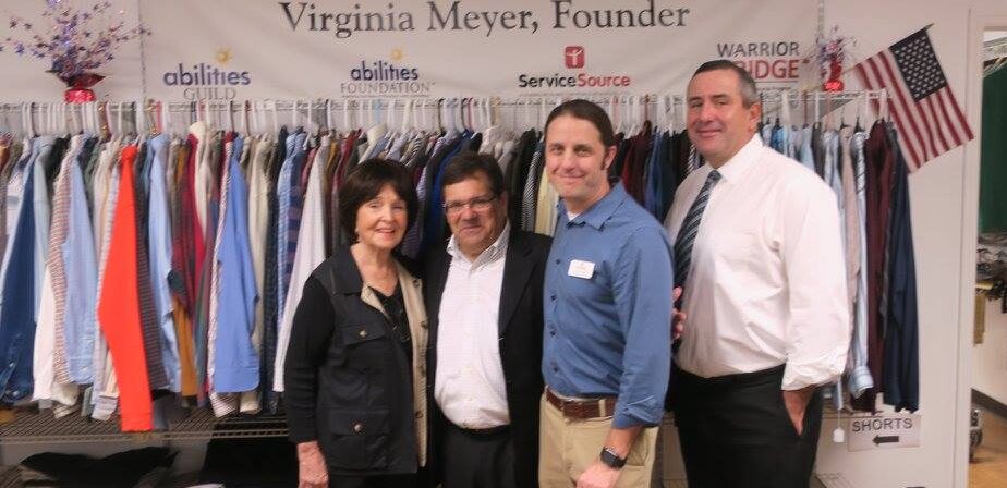 group smiling at camera in front of clothing rack