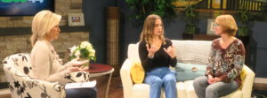 Three people sitting on furniture using hands to sign