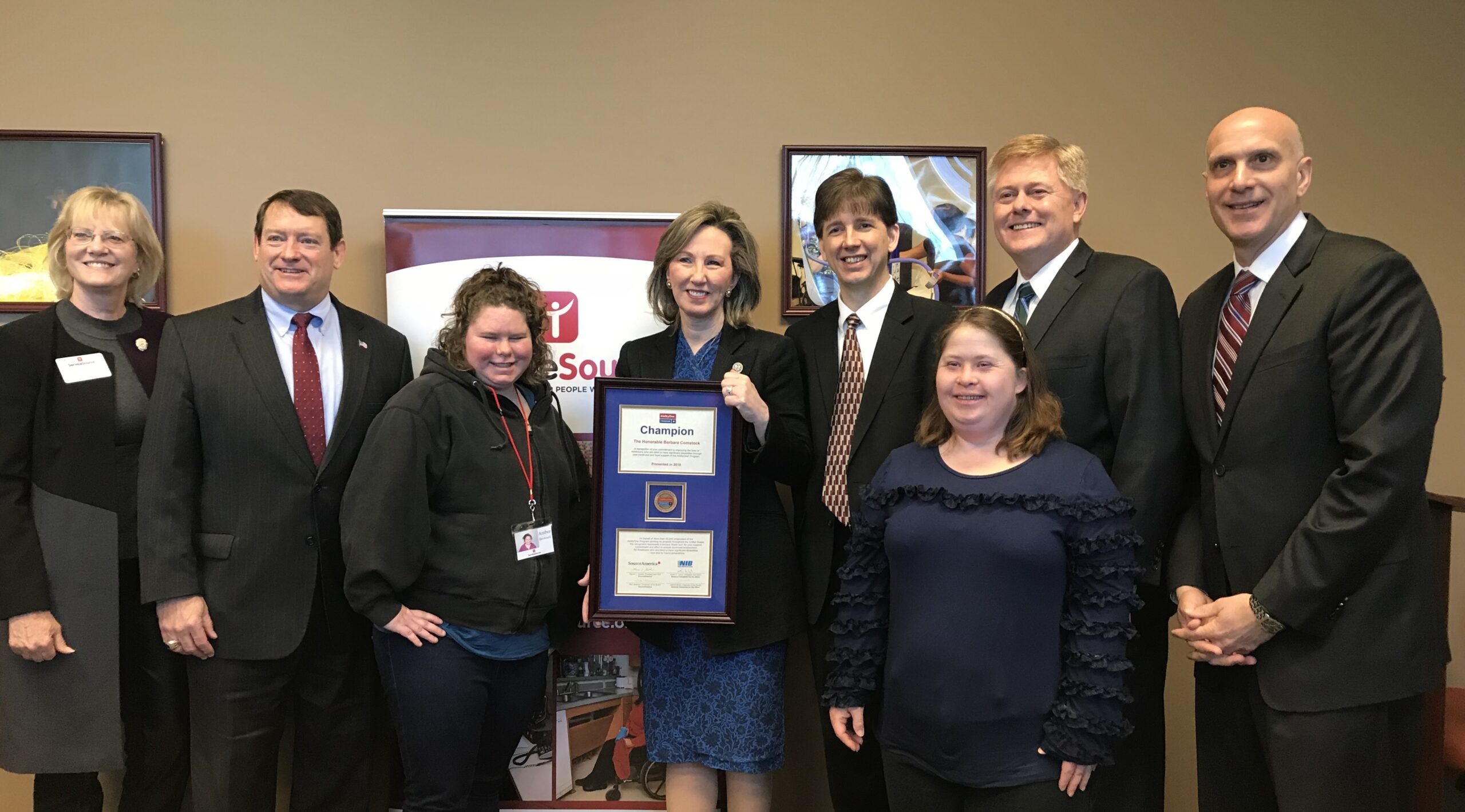 group of people smiling at camera with person in center holding plaque