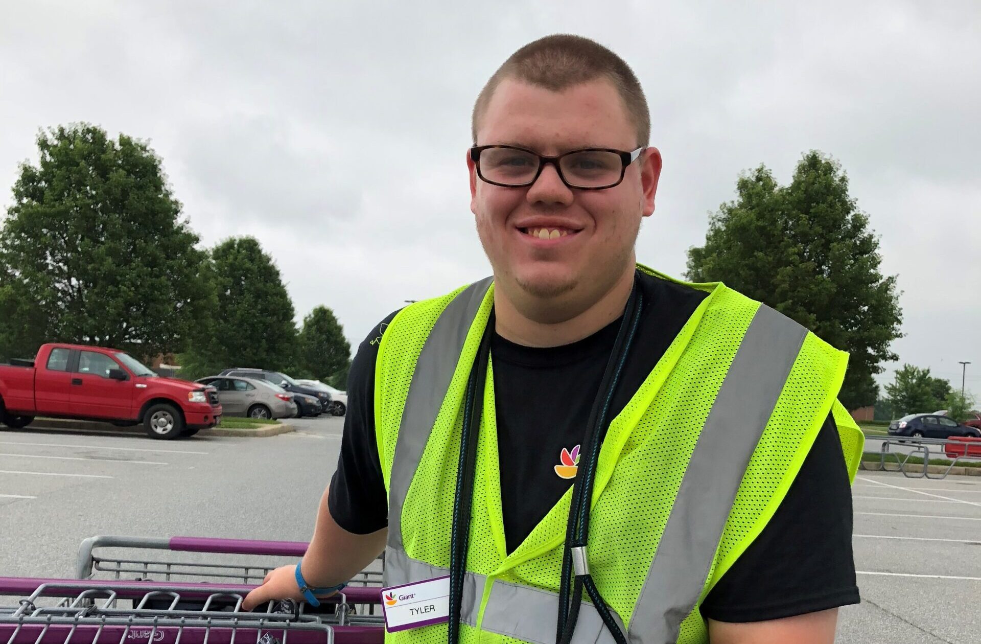 man in neon vest holding grocery carts smiling at camera