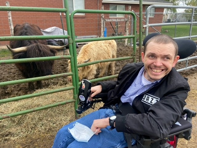 Person in wheelchair smiling in front of farm animals