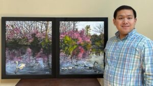 man poses next to colorful artwork on black canvas
