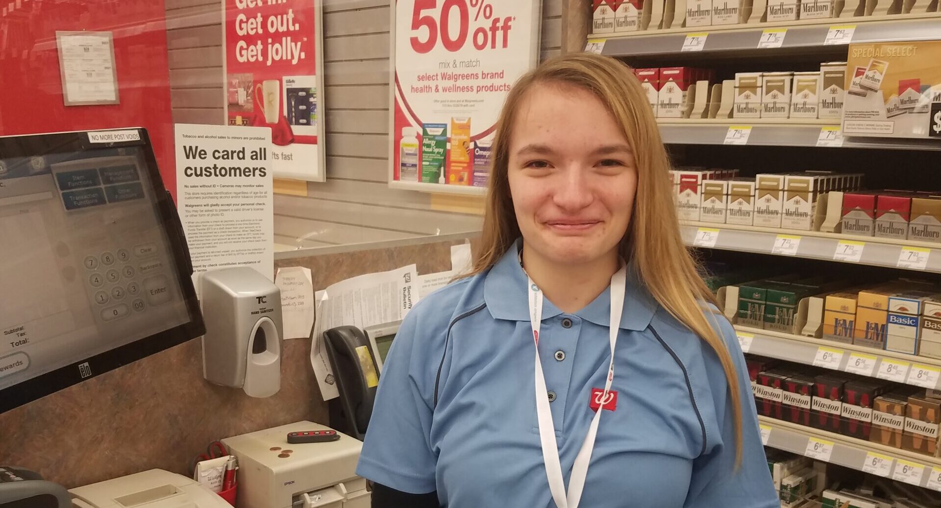 person smiling at camera behind cash register at Walgreens