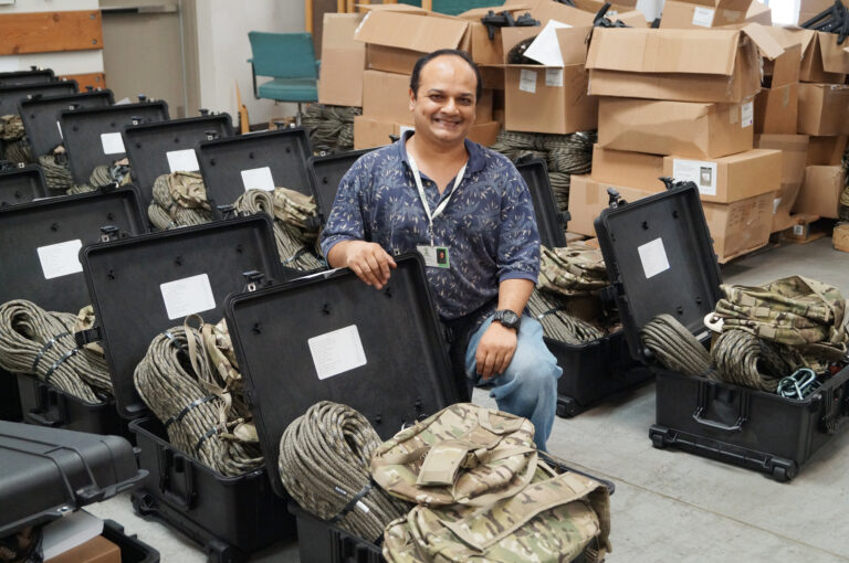 man kneeling in front of open box with military equipment