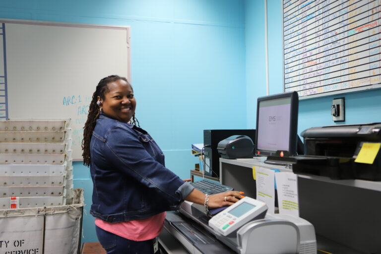 woman smiling at camera in front of large mail machine