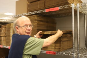 man with hands on cardboard boxes looking at camera