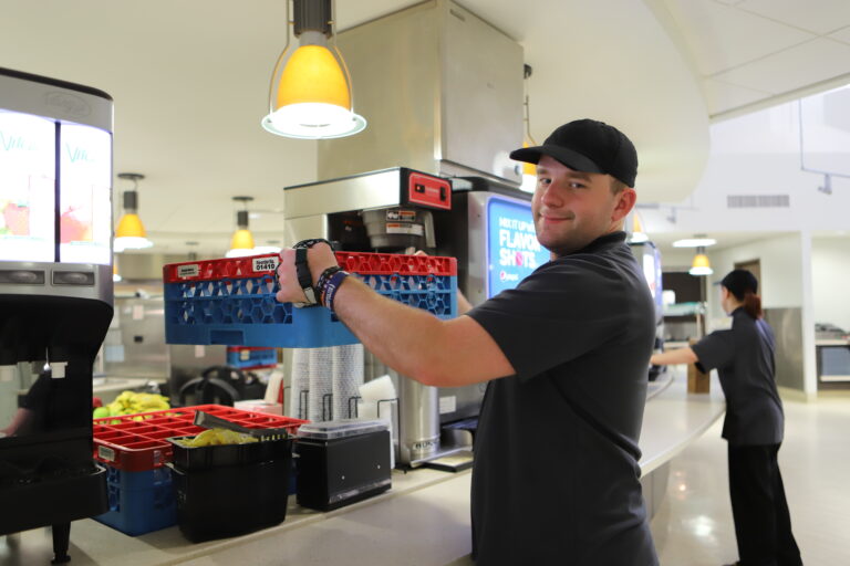 person holding up drink crate smiling at camera