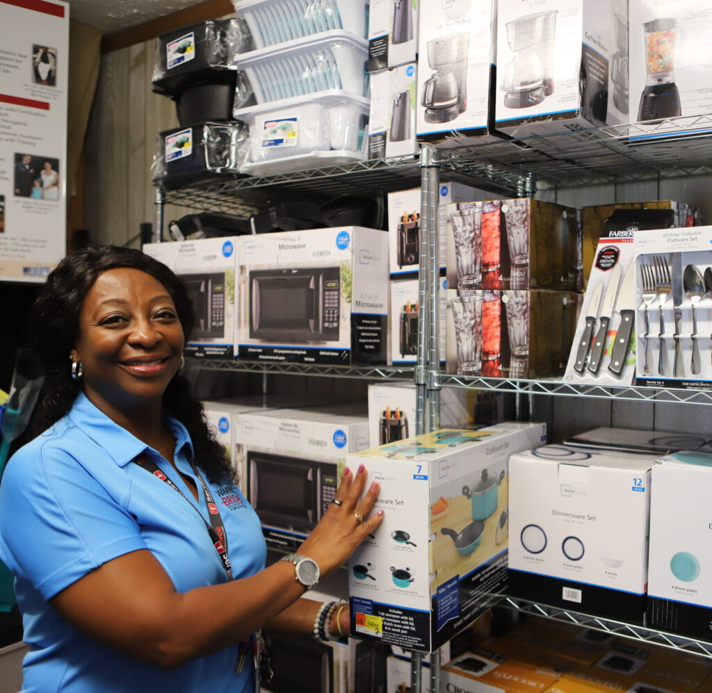 Person holding box standing in front of wall of appliances