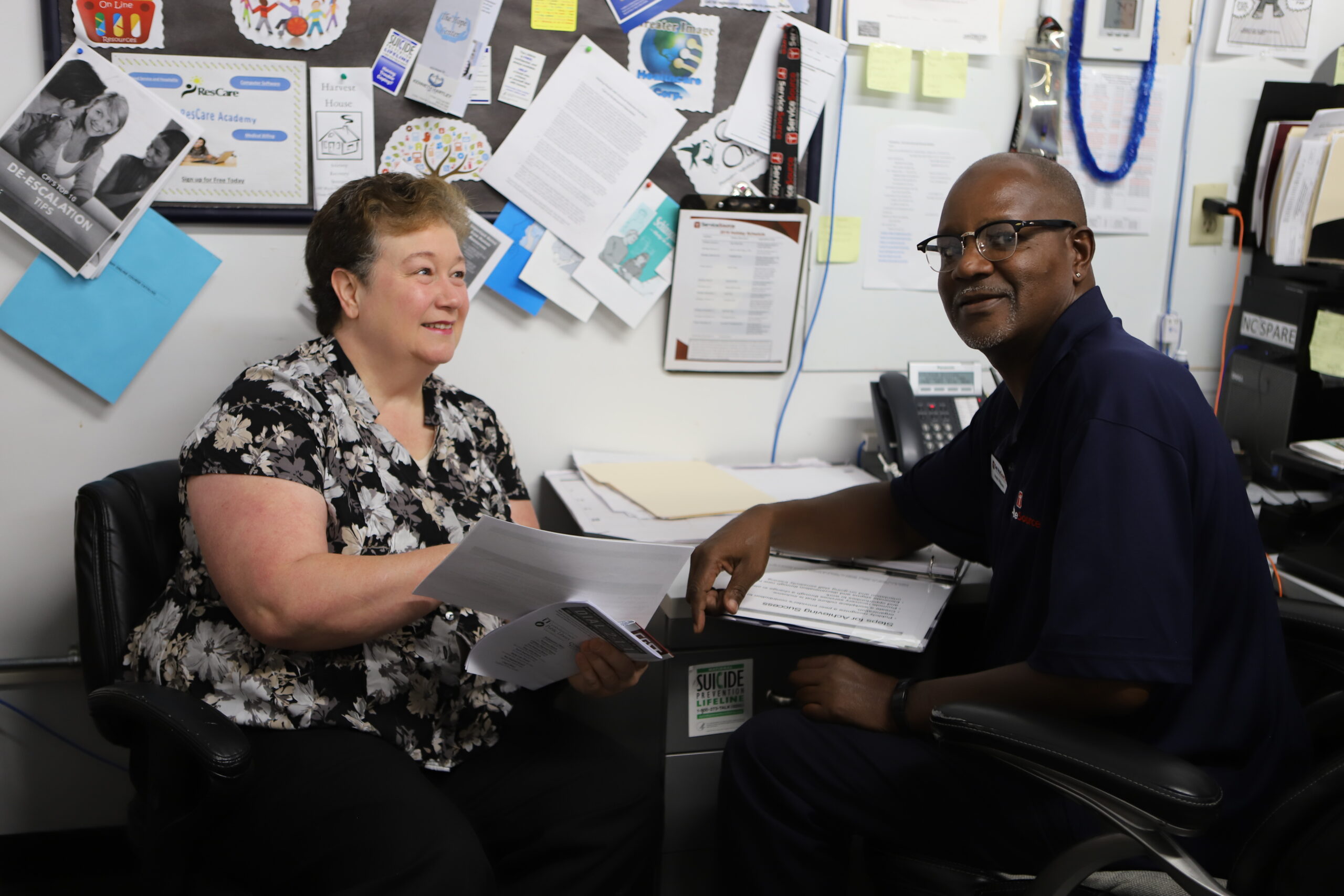 two people sitting at desk looking at camera