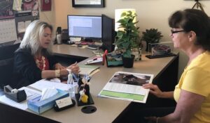 two people sitting across each other at desk talking