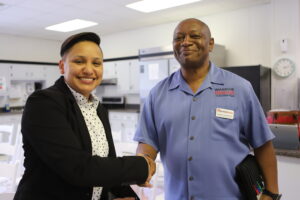 two people smiling at camera shaking hands