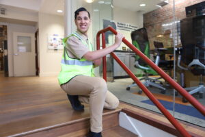 person smiling at camera with hands on stair rail