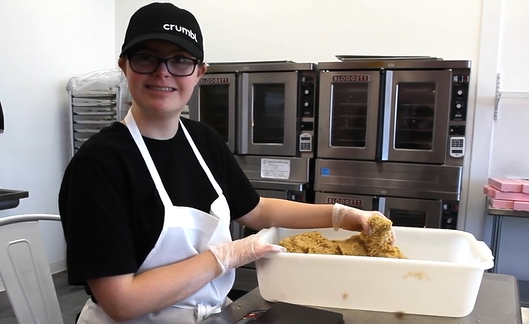 person smiling at camera with hands in dough