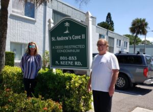 Two people standing outside condo residence in front of sign