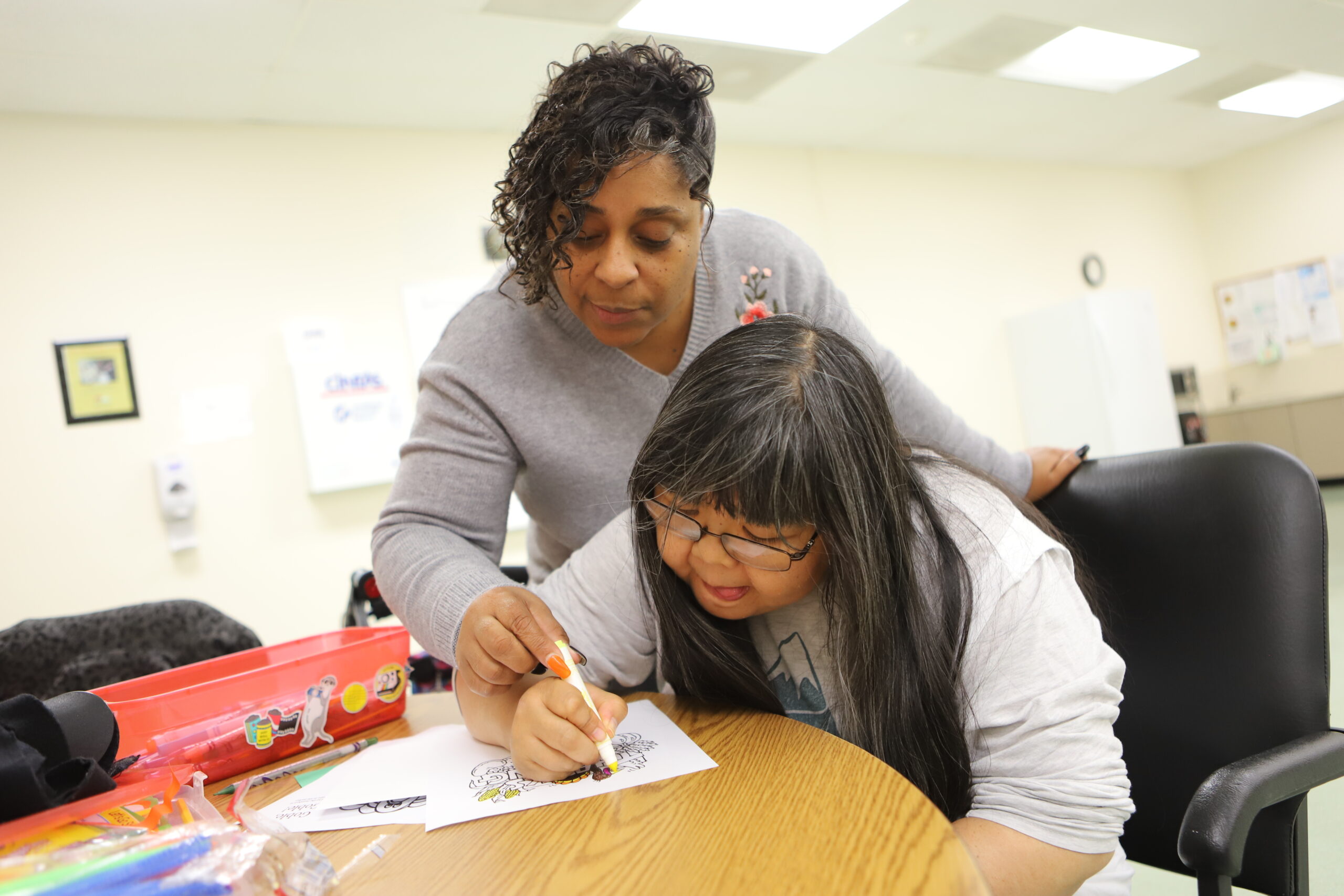 woman looking down helping another person write