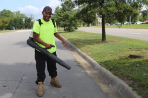 man smiling at camera holding leaf blower