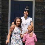 family of three outside front door of house
