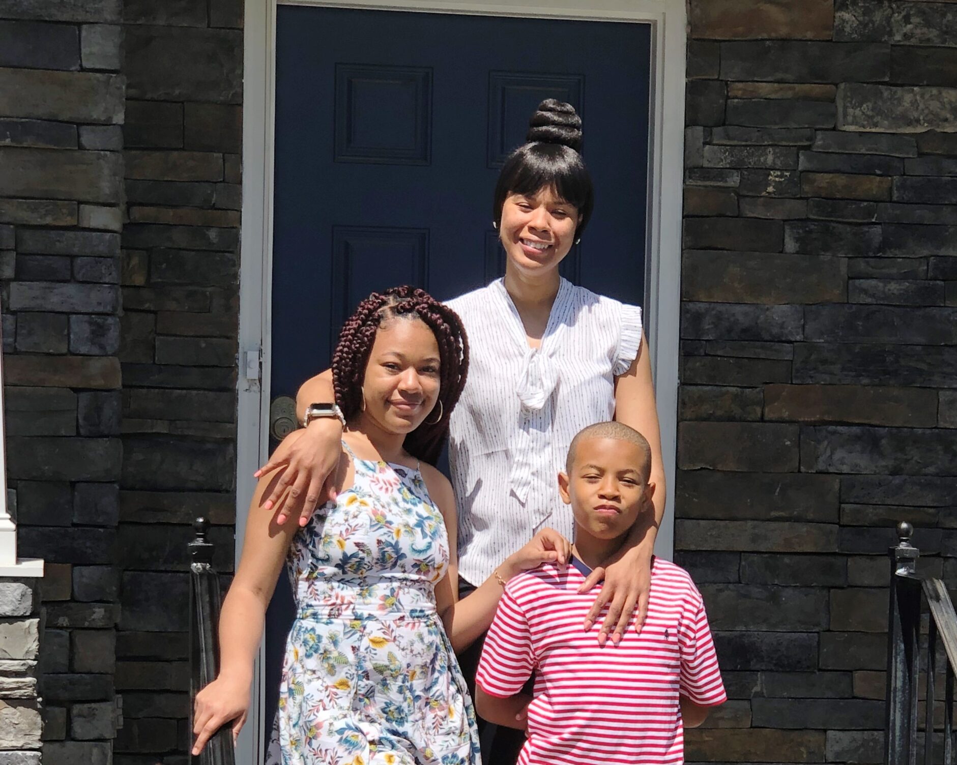 family of three outside front door of house