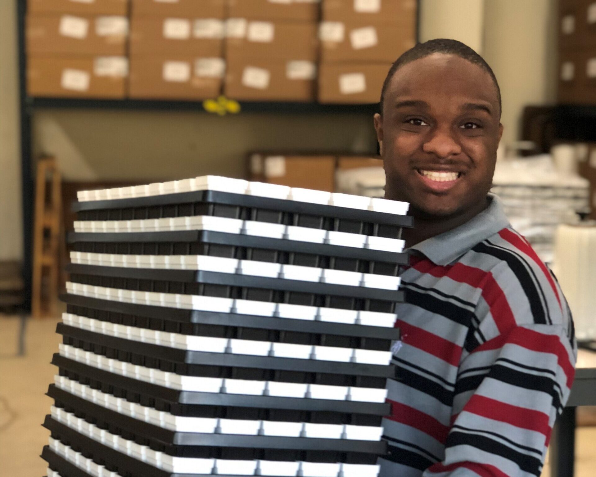 person smiling at camera holding small planting crates