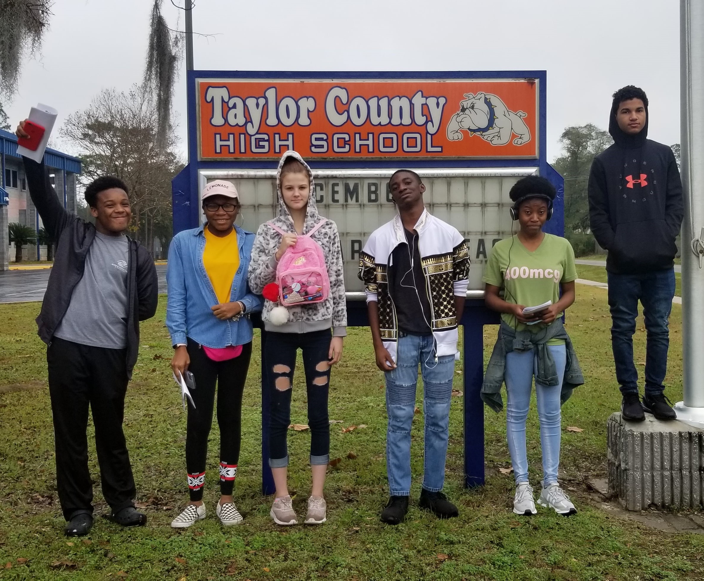 Group of young people standing in front of Taylor County High School sign