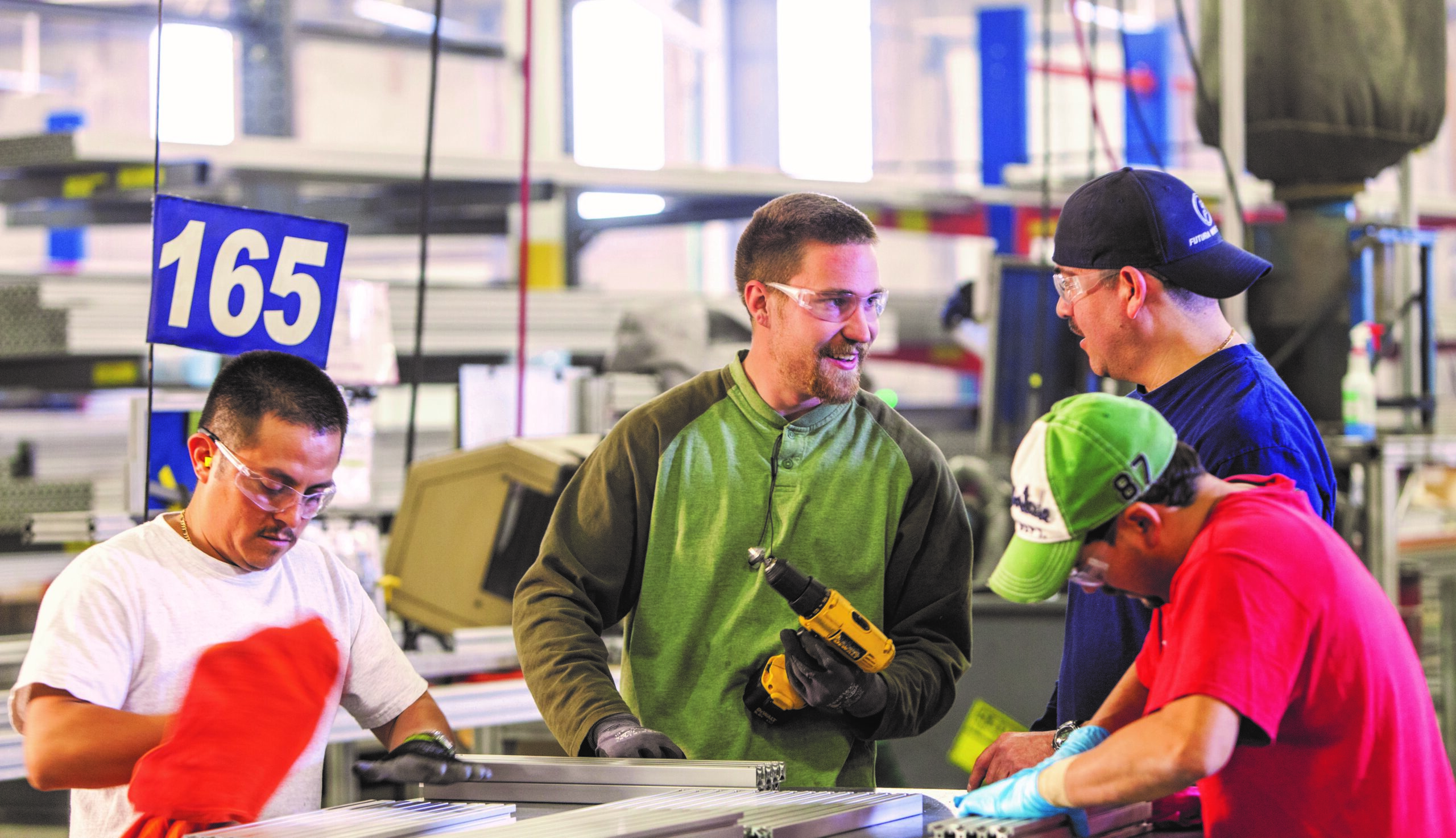 Person holding drill in warehouse talking to other employees