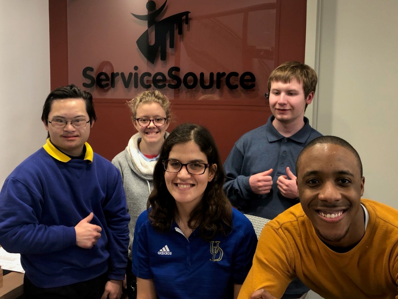 Group of youth sitting in front of sign that says ServiceSource