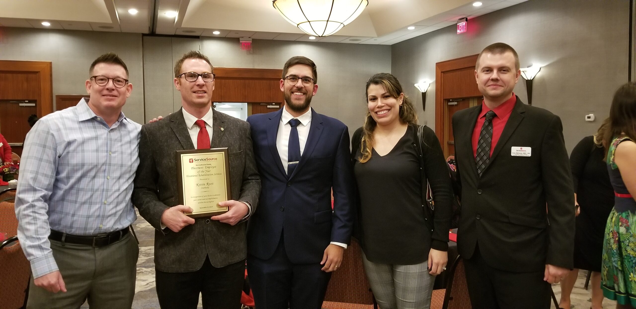 Group of people standing around person holding award plaque