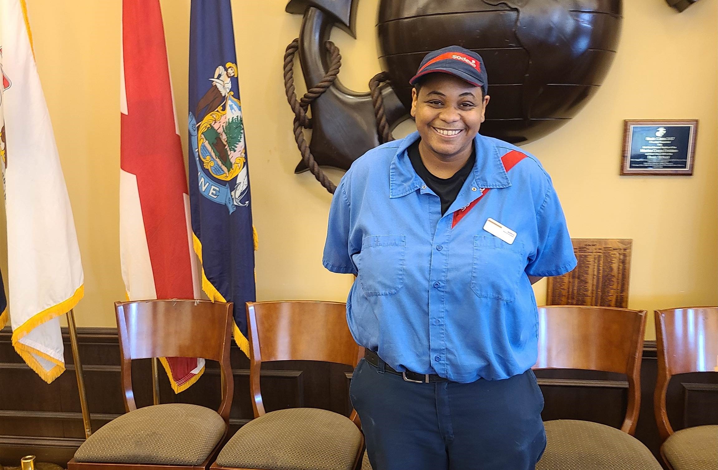 Person in uniform standing in front of military flags