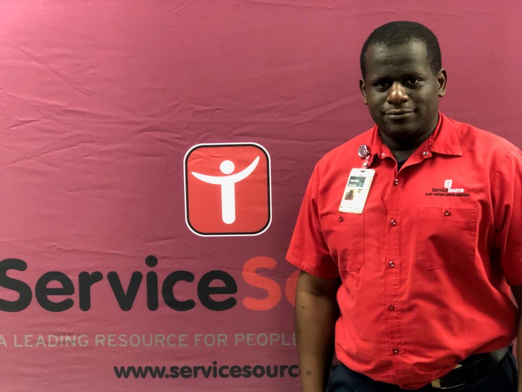 Person in uniform standing in front of ServiceSource logo