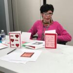 person at table with handmade cards