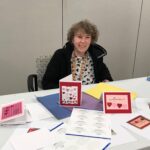 person sitting at table with handmade cards