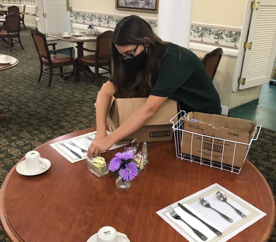 Person in dining room setting table