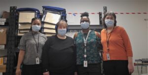 People posing for photo with masks in storage room