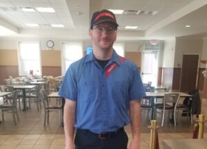 Person posing for photo in Sodexo uniform inside dining hall
