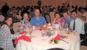 Group of people sitting around table of food and drinks